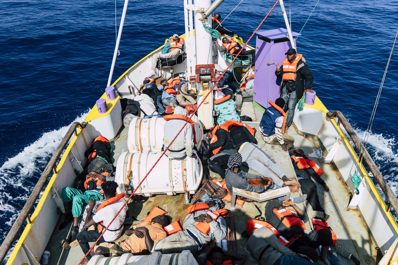 Gerettete in Rettungswesten auf dem Deck eines Search-and-Rescue-Schiffs im zentralen Mittelmeer